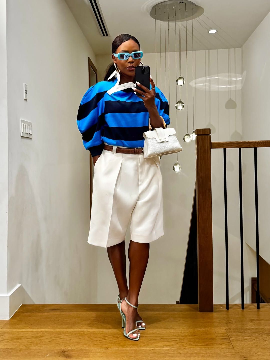 woman wearing stripe top with white shorts and bag summer capsule wardrobe essential
