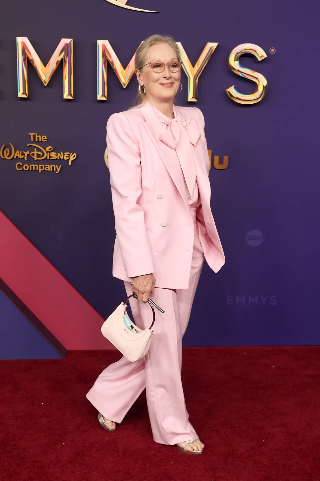 Model wearing a head-to-toe powder pink summer outfit with tailored blazer and pants, showcasing the powder pink summer trend 2025