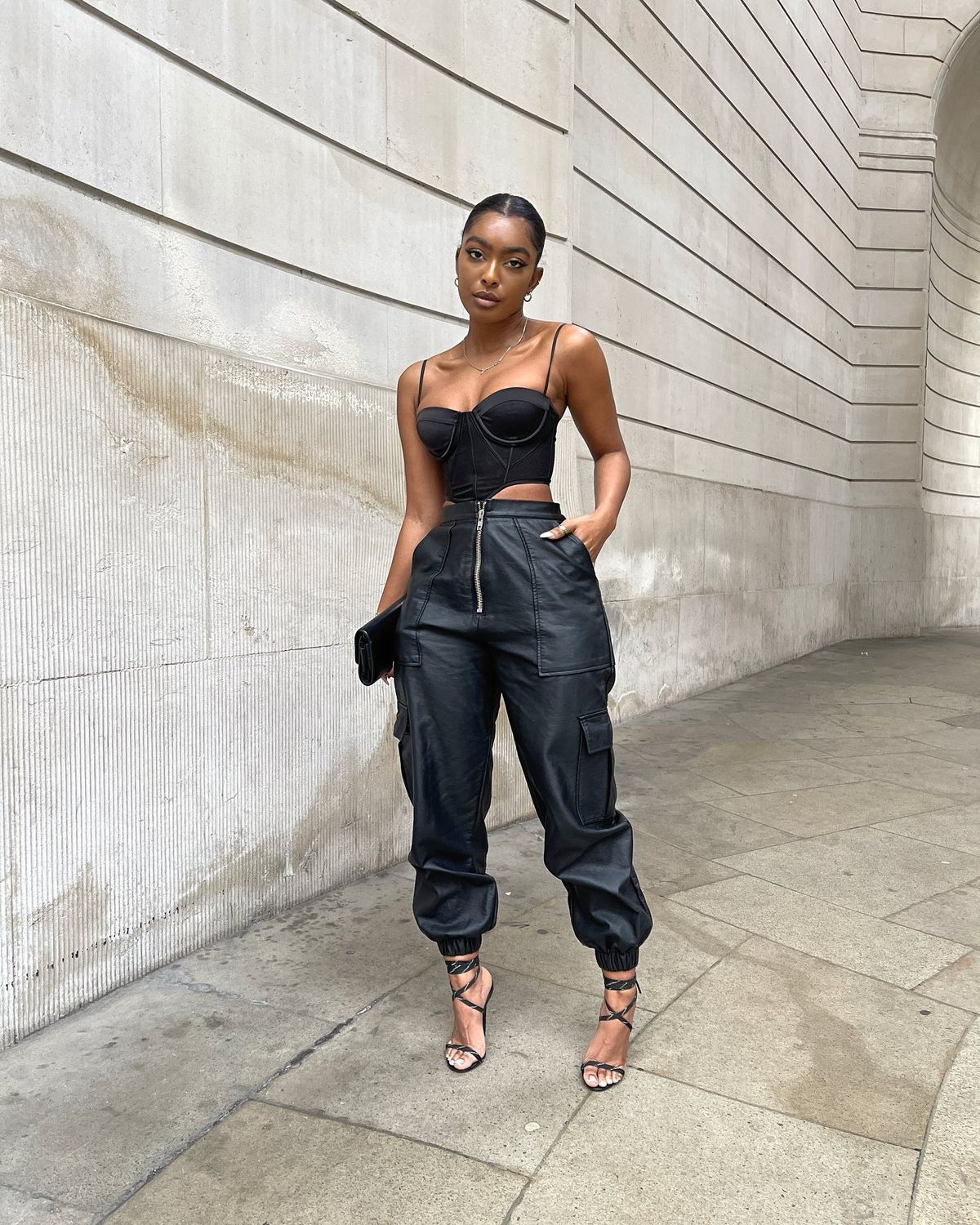 Женщина в корсете с черными погрузочными штанами и сандалиями