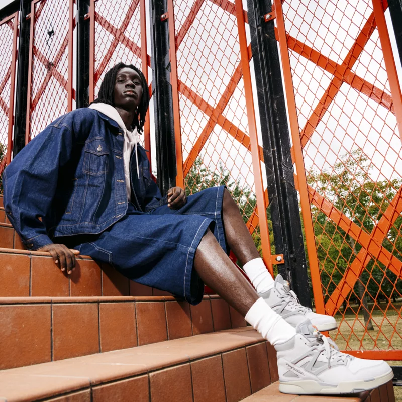 Модель ношения насоса Reebok Omni -Zone II с цветовыми акцентами PlayStation.