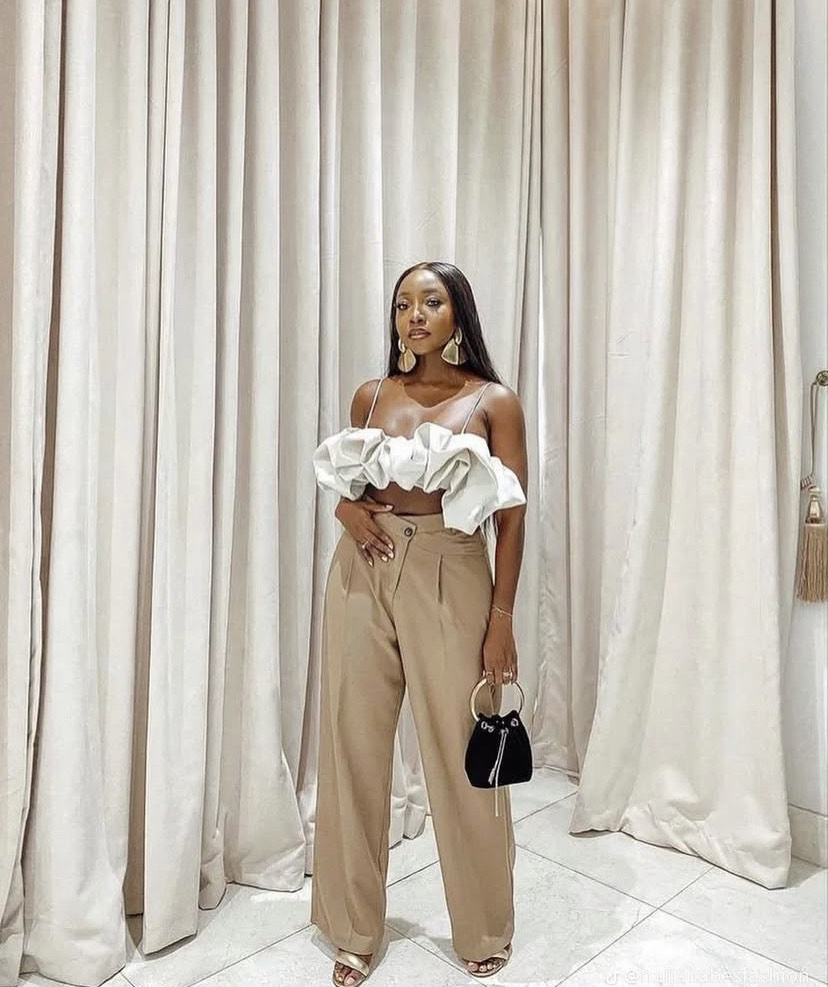 Женщина в укороченном топе с открытыми плечами и брюках цвета хаки — демонстрирует шикарные женские наряды в брюках цвета хаки и на каблуках.