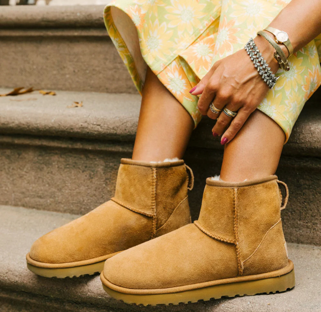 Женщина укладывает угги с дубленкой и зимними аксессуарами.