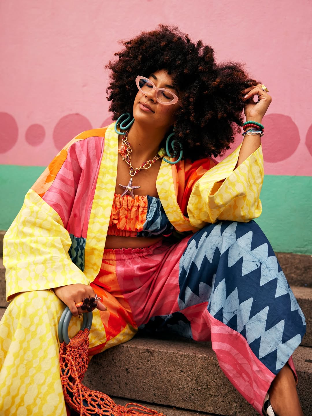 Женщина в узорчатом костюме с афро-волосами.