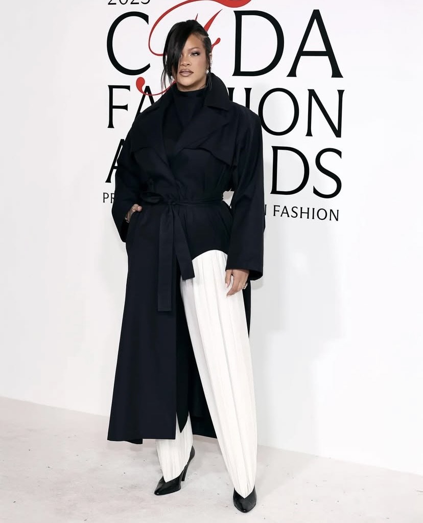 Rihanna in a tailored black coat and white pleated trousers at the CFDA Awards showcasing intentional celebrity looks.