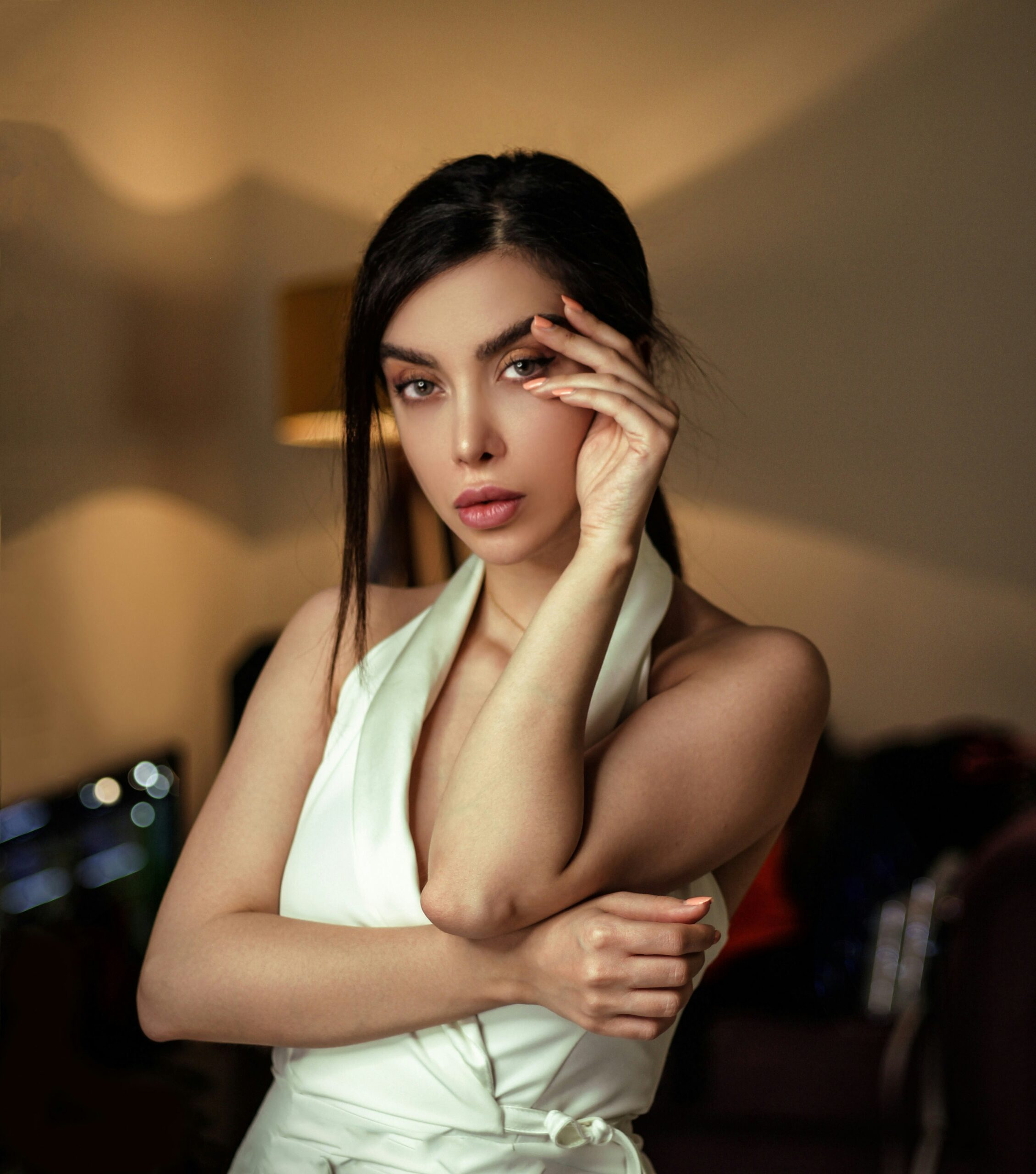 женщина в белом наряде трогает лицо густыми бровями, которым нужен гель