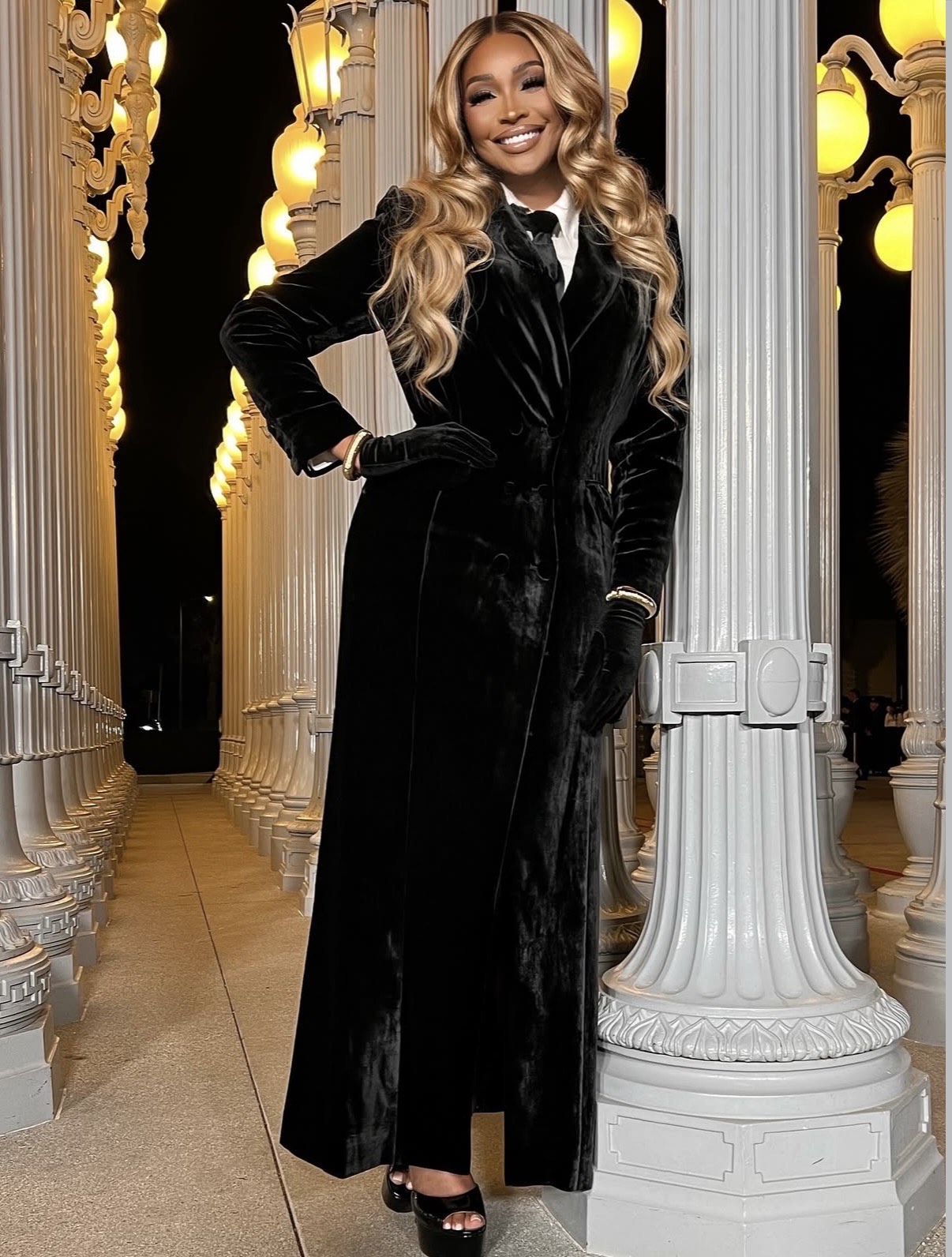 Cynthia Bailey in a black velvet tuxedo-style dress layered over a white shirt, a refined interpretation of celebrity new year outfits.