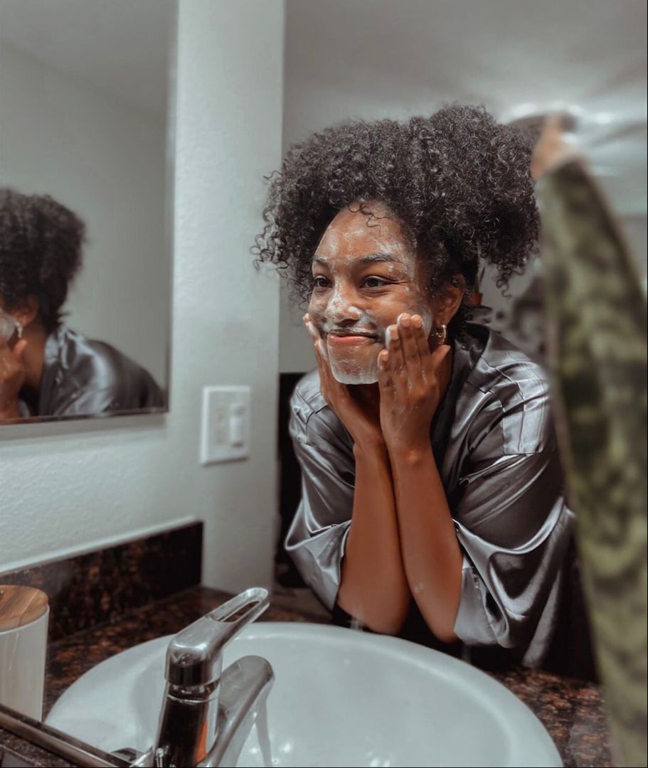 Woman washing her face with a gentle face cleanser for winter in a softly lit bathroom