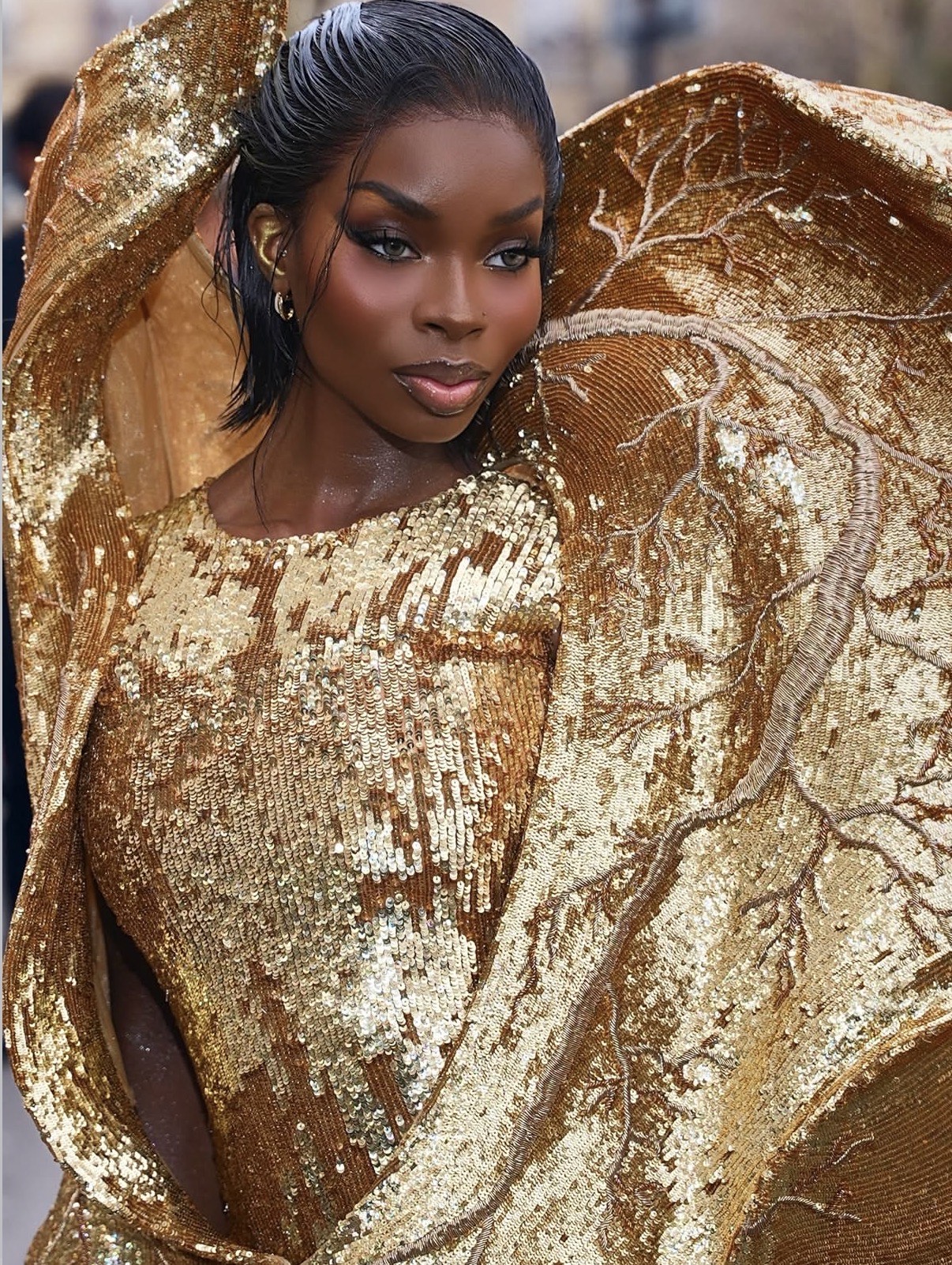 Olandria wears glowing bronze eye makeup and radiant skin at Paris Fashion Week, showcasing editorial beauty aligned with 2026 Grammys best beauty trends.