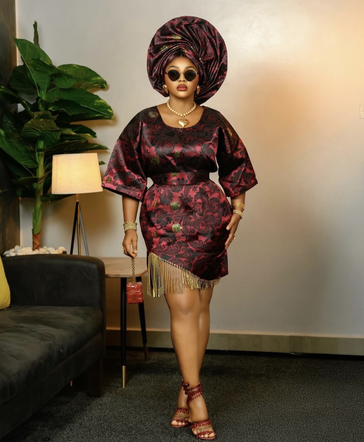 Mercy Aigbe in red and black Oleku outfit with gold fringe detailing — vibrant Nigerian fashion