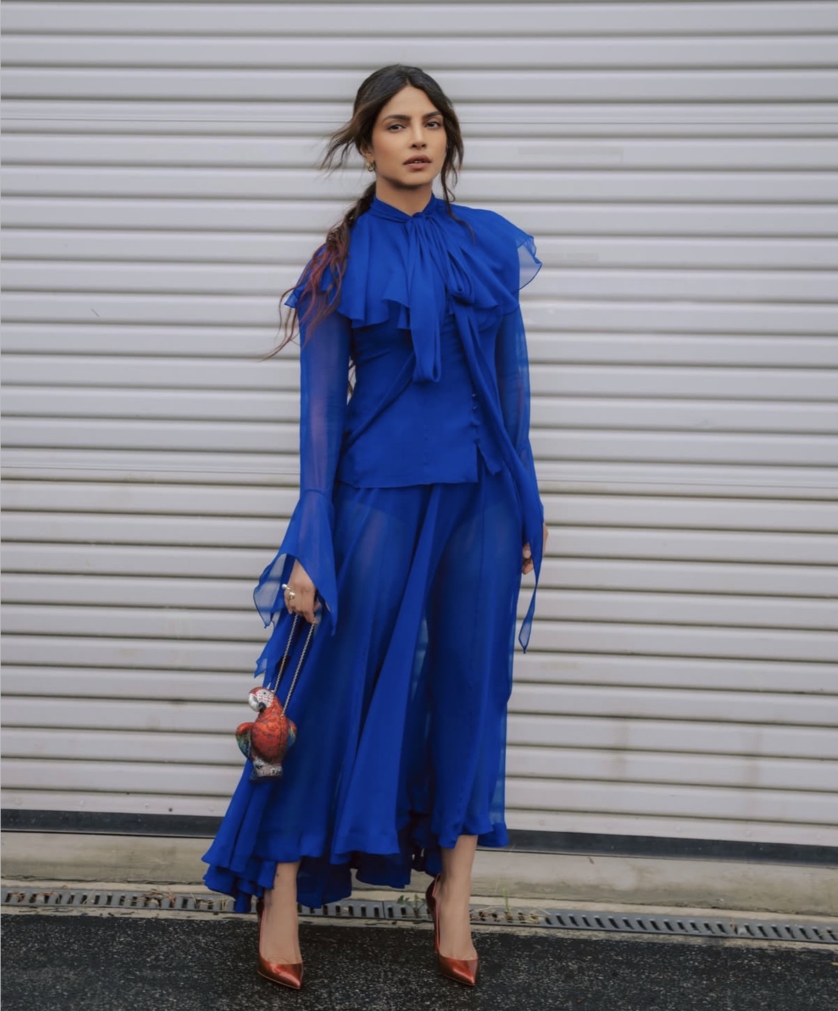 Priyanka Chopra in an electric blue ruffled Tidal gown with oversized bow detail and asymmetrical hem during her press tour.