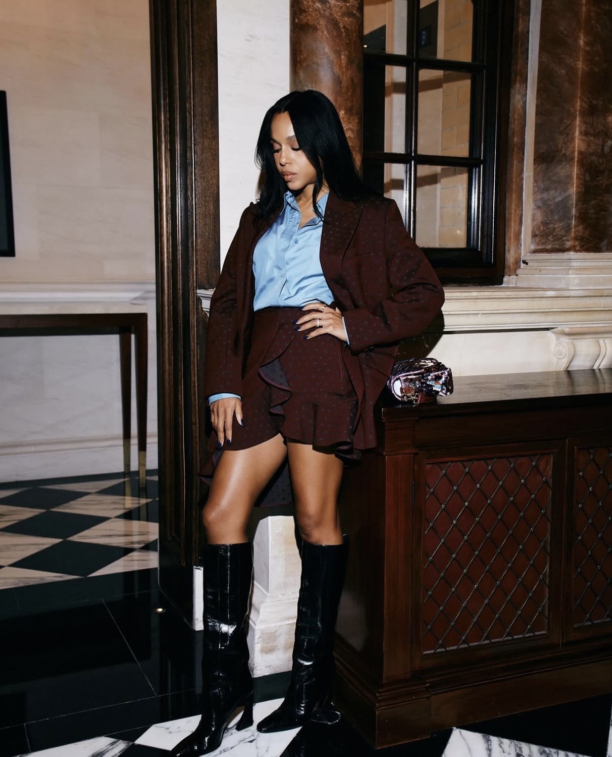 Kerry Washington in a burgundy oversized blazer and ruffled mini skirt styled with a blue button-down and patent knee-high boots