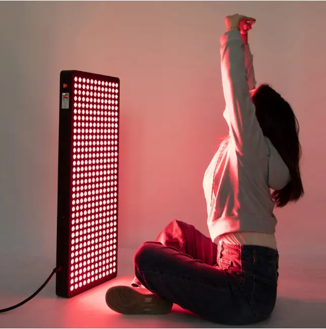 Woman using red light panel for skin treatment at home