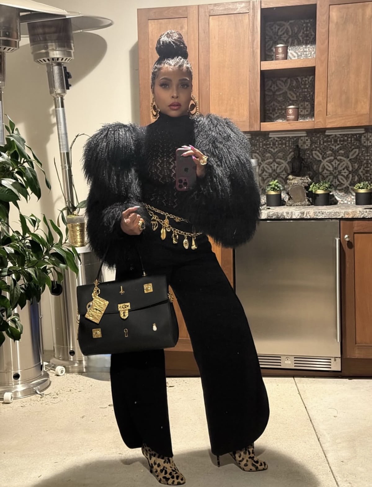 Taraji P. Henson in an all-black outfit with fuzzy sleeves, wide-leg trousers, and a gold chain belt— celebrity street style fashion 2026