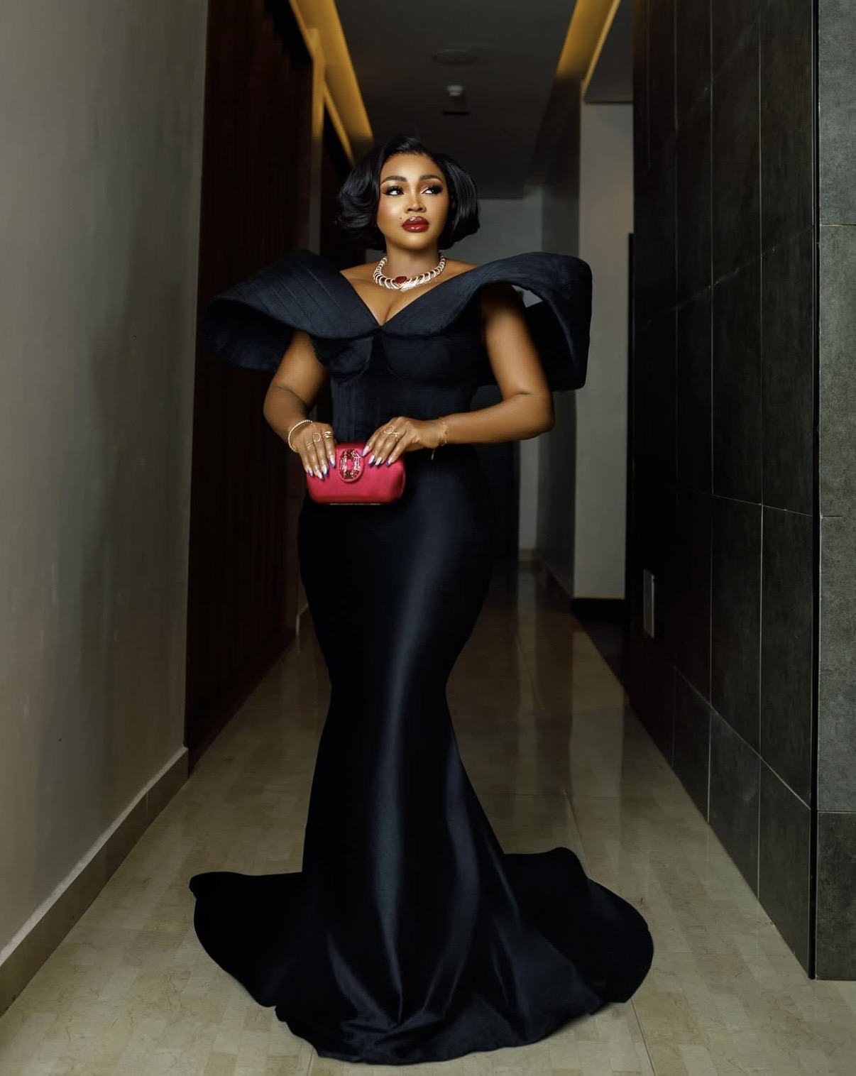 Mercy Aigbe in black gown with statement sleeves and red accessories, embodying Nigerian elegant styles