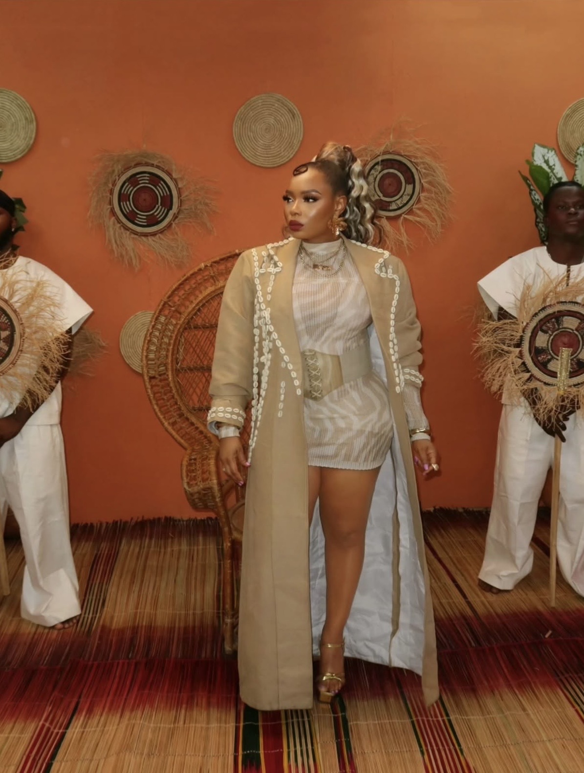 Yemi Alade in cowry-embellished trench coat and mesh mini dress, reflecting bold Nigerian elegant styles