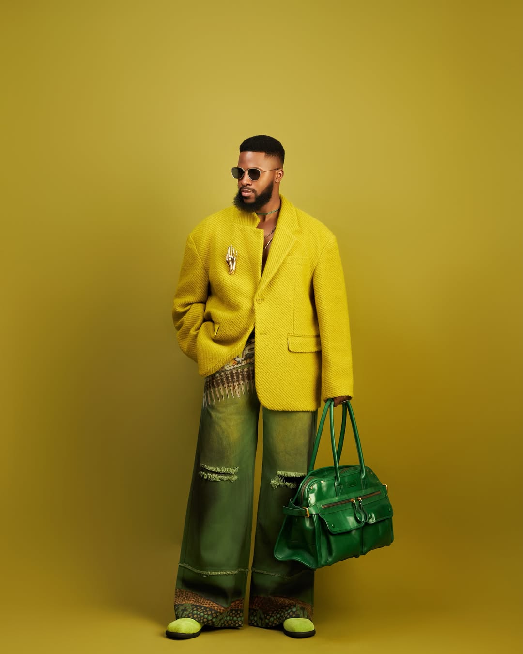 man wearing all green outfit of sweater, jeans, and a bag