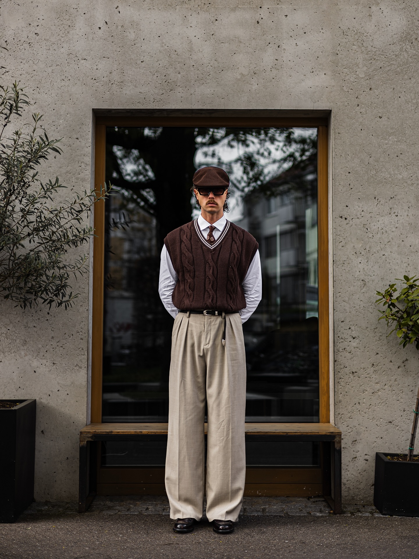 Man in an oatmeal sweater vest layered over a white oxford shirt